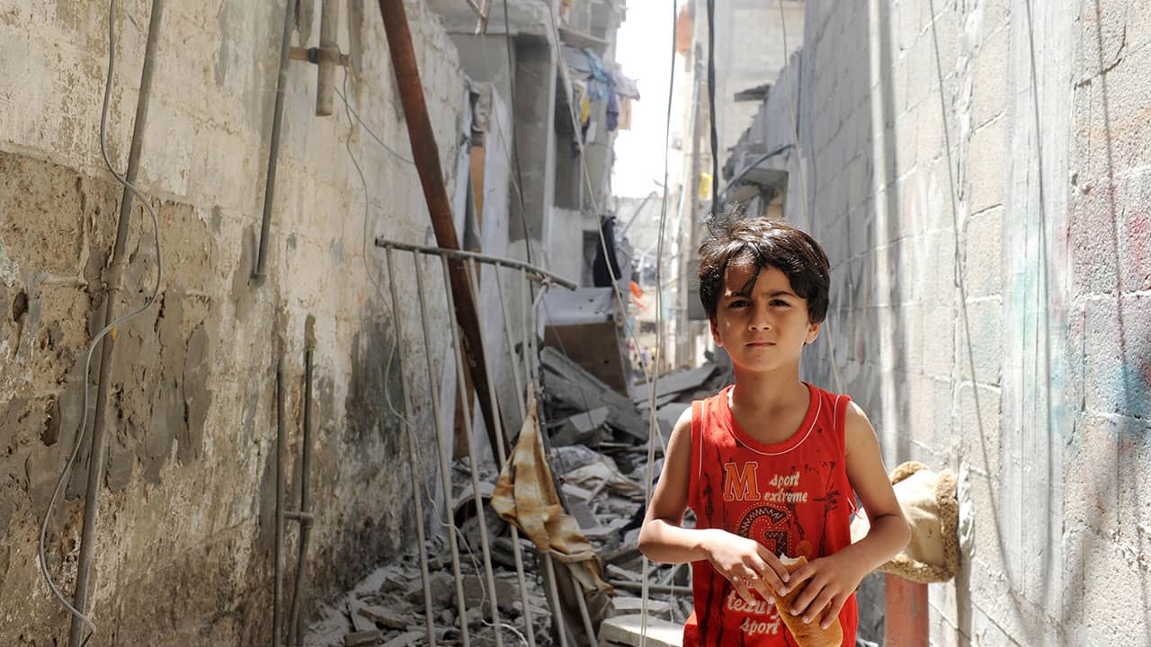 A young Palestinian boy walks through the remains of a house targeted by an Israeli air strike near a beach refugee camp west of Gaza City. UN Photo /Shareef Sarhan