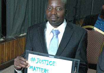 Mr. Fox Odoi, MP, PGA Member, the MP petitioning the Constitutional Court to nullify the "Anti-Gay Law" adopted without a quorum by Parliament. In this photo, Mr. Odoi testifies his commitment to justice displaying the hash-tag of IJD.